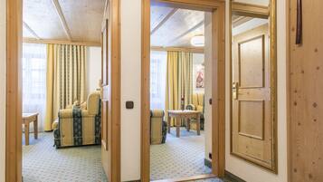 A hotel room with a wooden door, a patterned carpet, a sofa, and a small table.