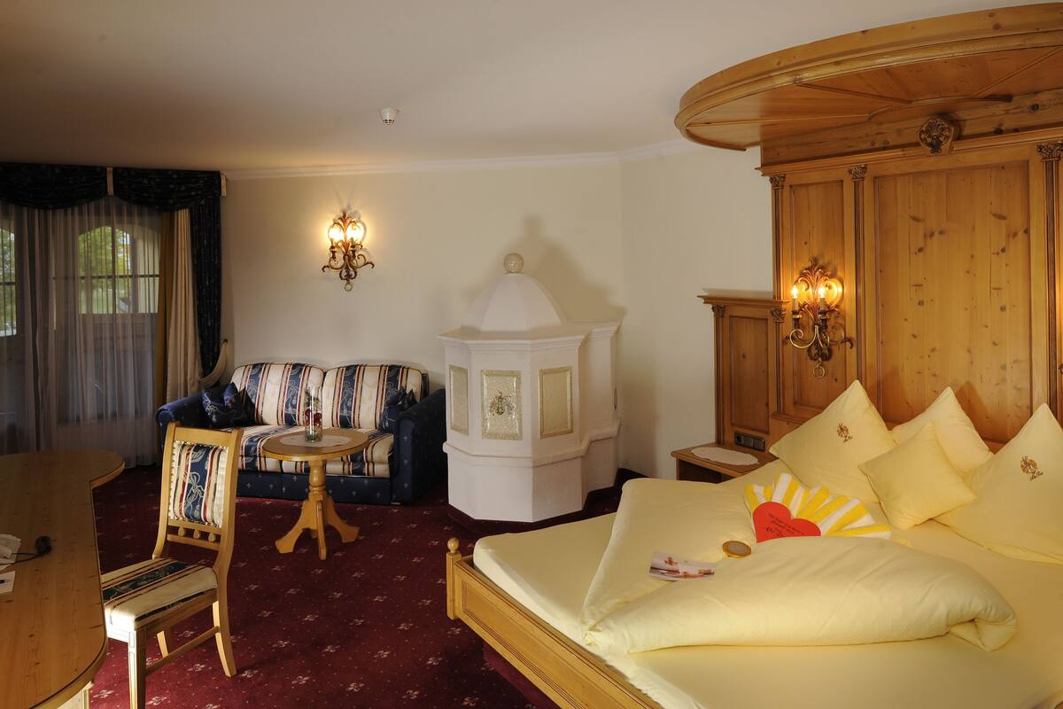 A hotel room with a bed, a sofa, a small table, and a chair.