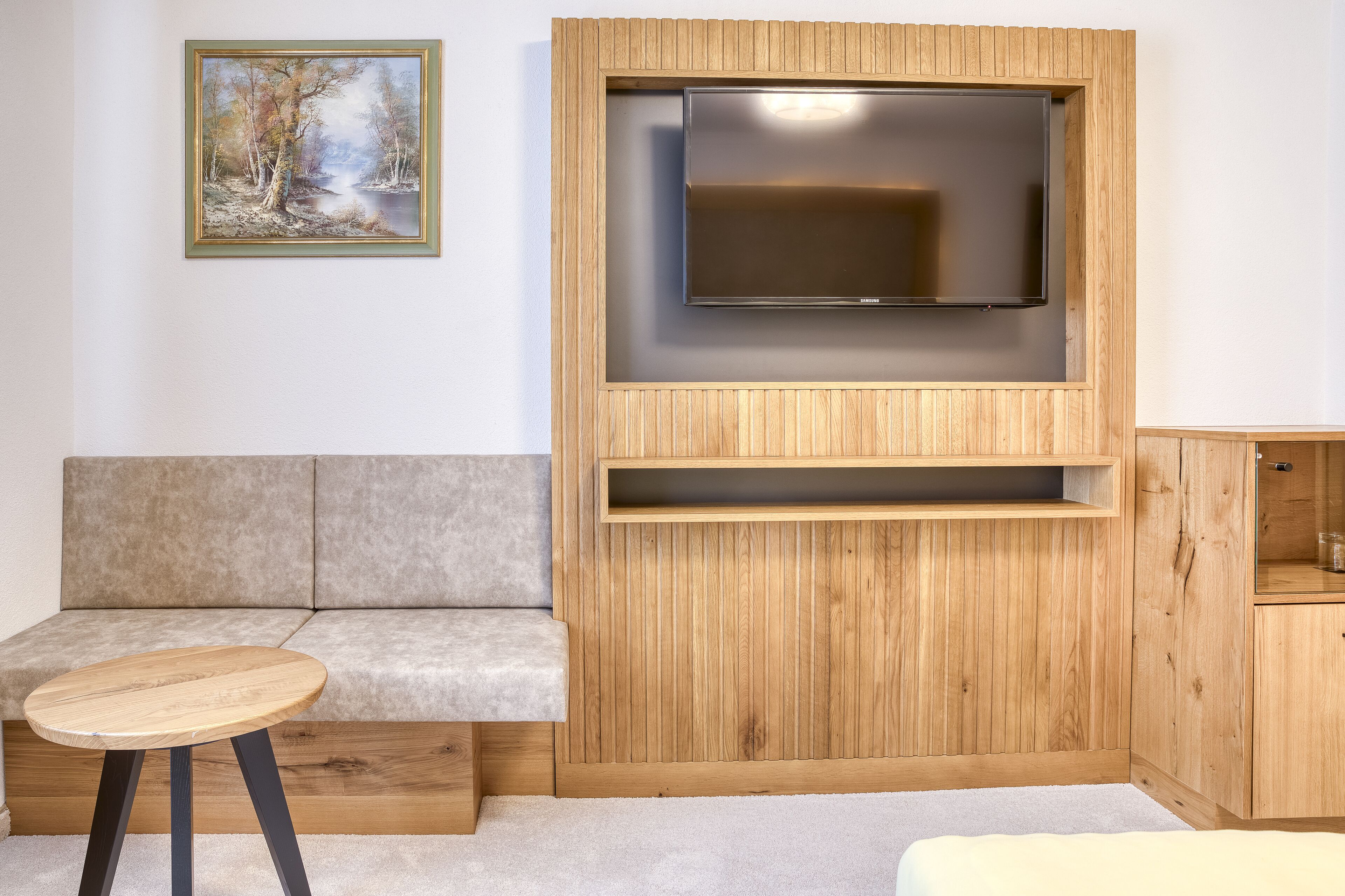 A modern living room with a wooden TV stand, a sofa, and a small round table.