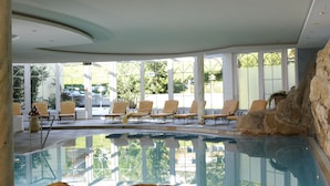 Uma área de piscina interna com espreguiçadeiras e uma formação rochosa.