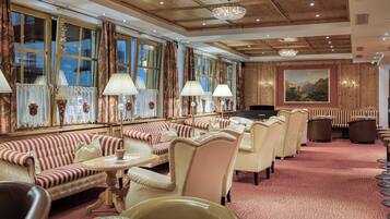 Eine Hotelhalle mit gestreiften Sofas, einem Chandelier und einem Gemälde an der Wand.