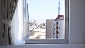 A window with a view of a cityscape, including a prominent tower. - Vessel Inn Ueno Iriya Station (Tokyo)