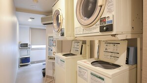 A laundry area with multiple washing machines and a microwave. - Vessel Inn Ueno Iriya Station (Tokyo)