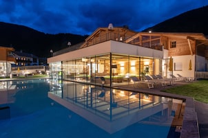 Una piscina techada, una piscina al aire libre, sombrillas