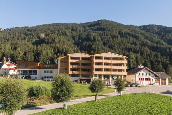 Un hotel de varios pisos con diseño moderno, situado en una zona montañosa y vistas a un bosque denso.