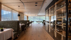 Un restaurante con pisos, mesas y sillas de madera, y una exhibición de vinos a la derecha.