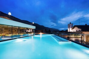 Una piscina con una barrera de vidrio, rodeada de edificios y una montaña al fondo.