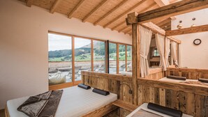 Habitación de cabaña de madera con una cama, un banco y un amplio ventanal con vistas al exterior.