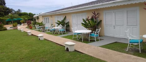 A building with a covered outdoor seating area, a paved walkway, and a well-maintained lawn.