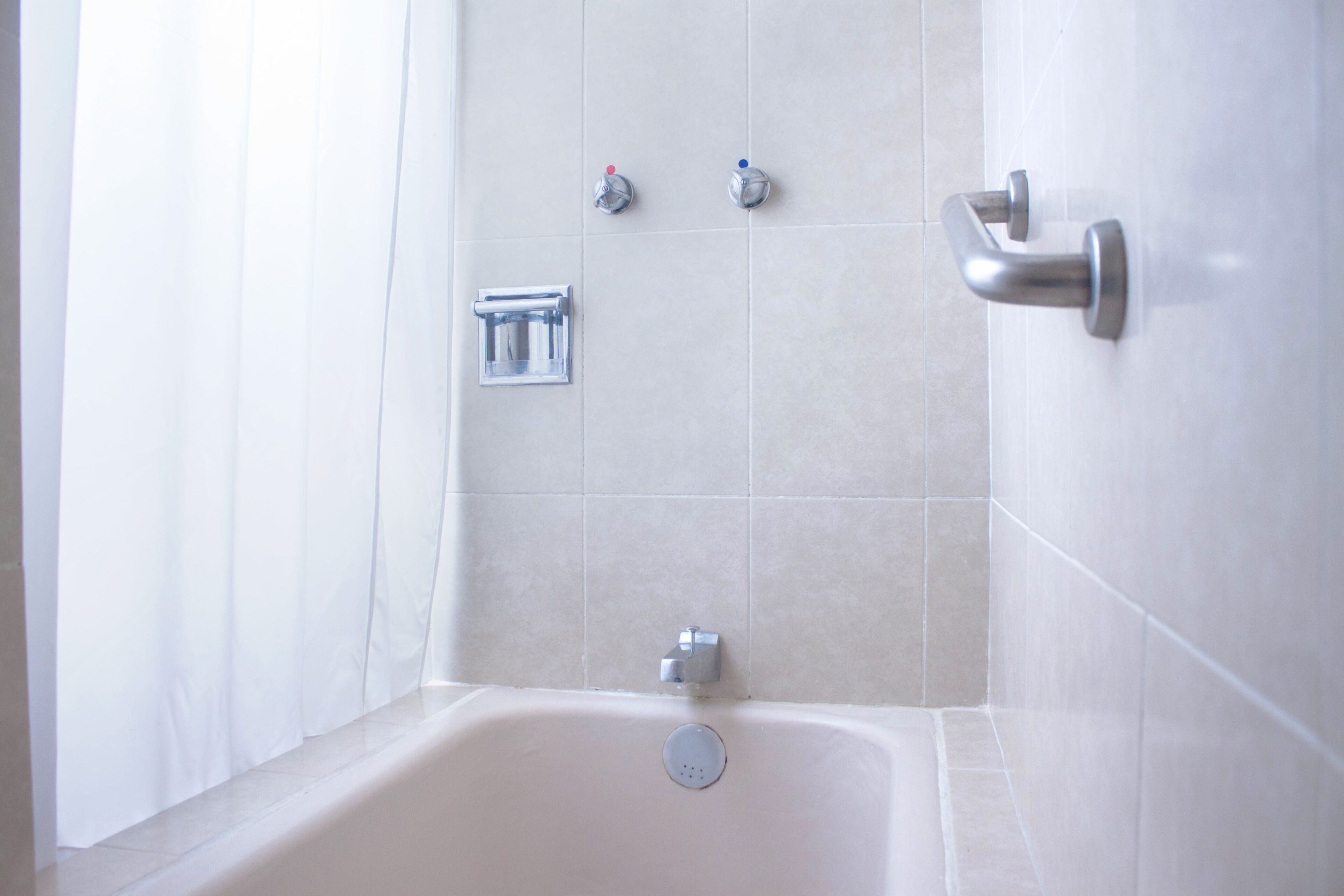 A bathroom with a bathtub, a towel rack, and a showerhead.