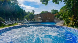 Piscina con un edificio de piedra al fondo, rodeada de vegetación.