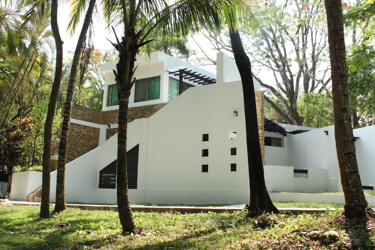 Un edificio moderno con fachada blanca, detalles de piedra y techo inclinado.