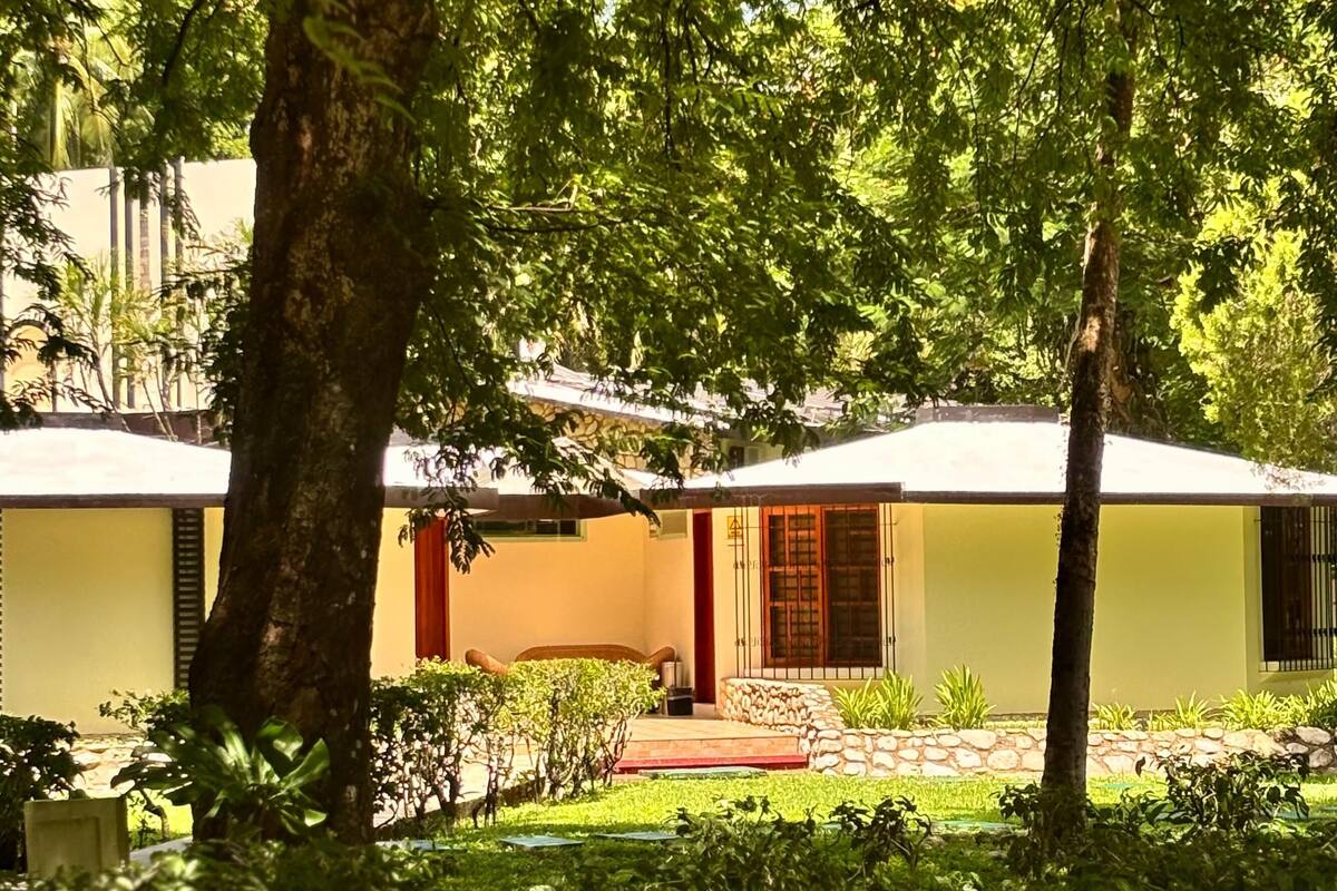 Un edificio de fachada amarilla, una puerta roja y un camino de piedra que conduce a la entrada.