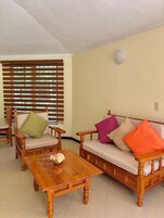 Un salón con muebles de madera, una mesa de centro y una ventana con persianas.