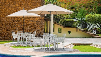 Alberca al aire libre, sombrillas en la alberca y camastros