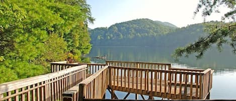 A wooden dock with a railing, a number '8' sign, and a view of a lake with mountains in the background.