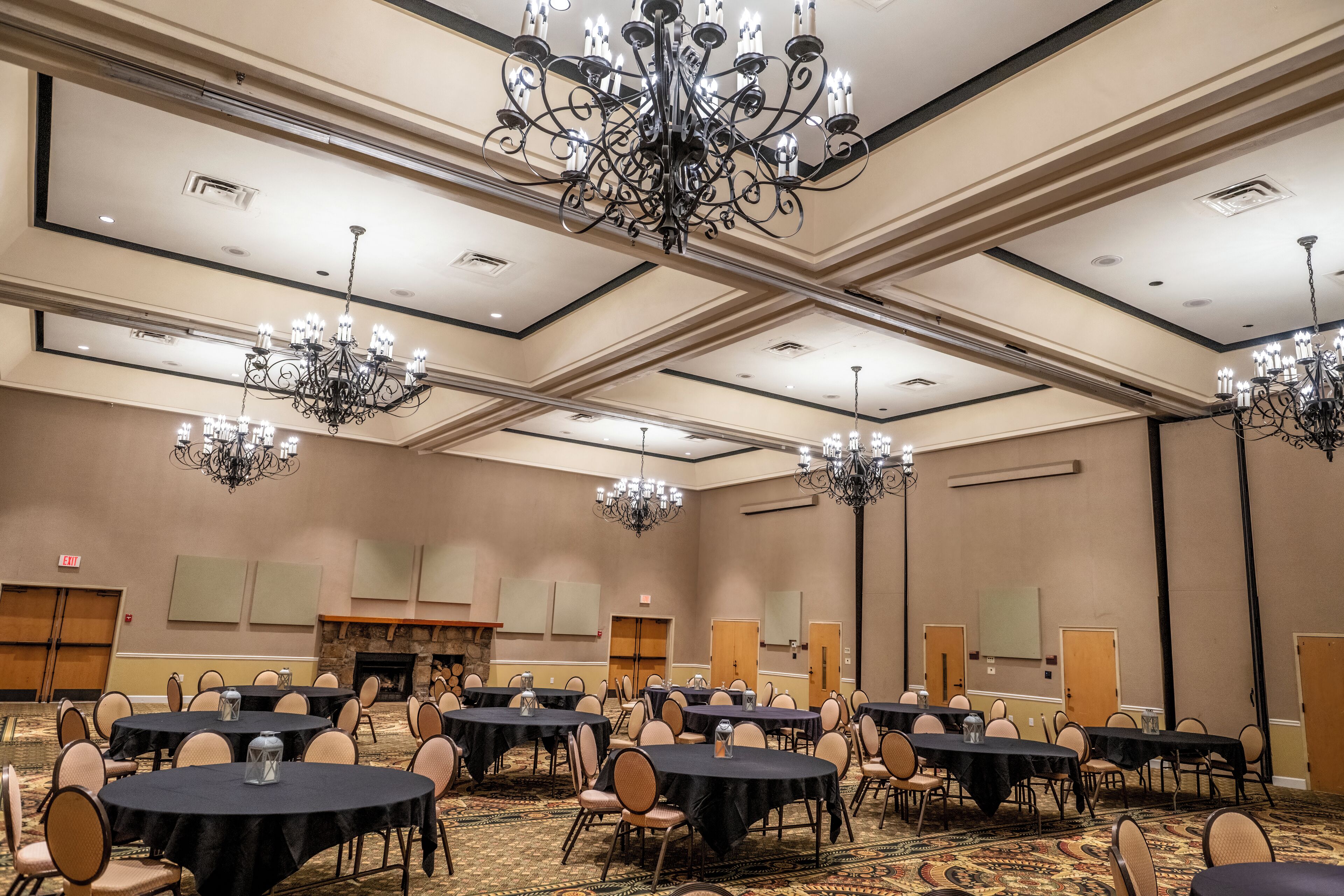 Un salón de conferencias amplio con varias mesas redondas, sillas y candelabros.