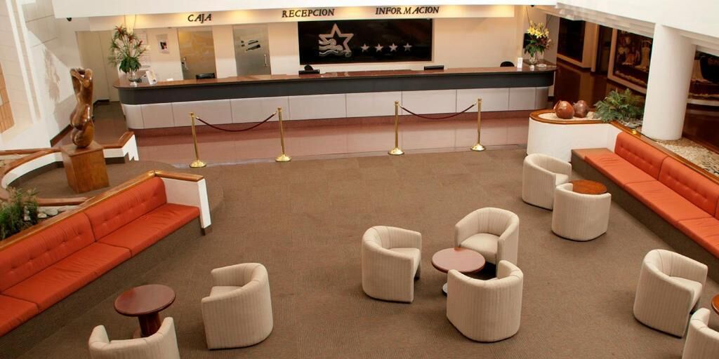 A hotel lobby with a reception desk, seating area, and a statue.