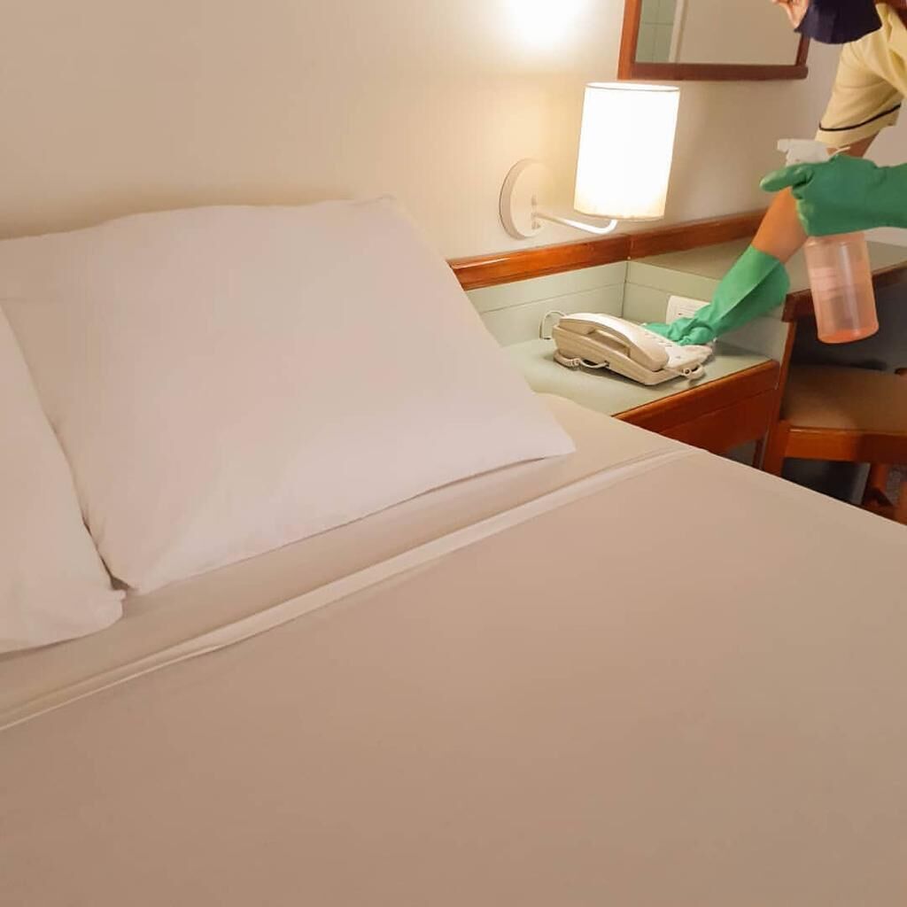 Ein Hotelzimmer mit einem aufgeräumten Bett, einem Nachttischtelefon und einem Nachttisch mit einer Lampe.