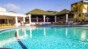 Una piscina con agua cristalina, rodeada de sillones de descanso y zonas de estar cubiertas.