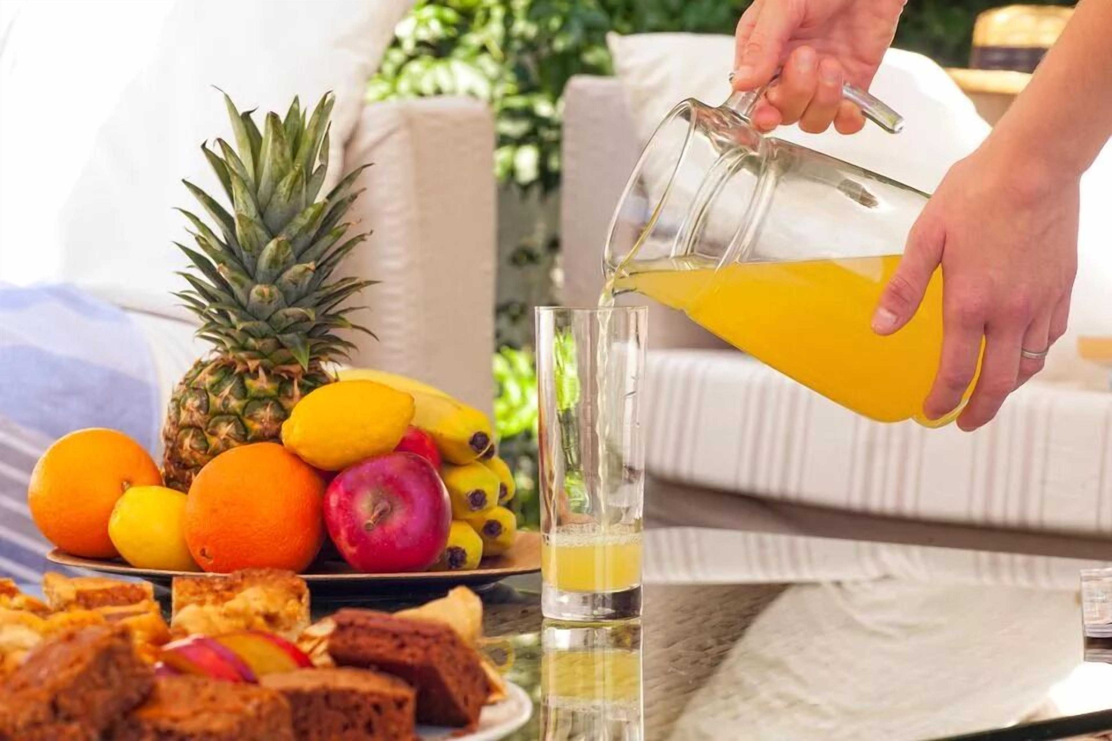A person pouring orange juice into a glass.
