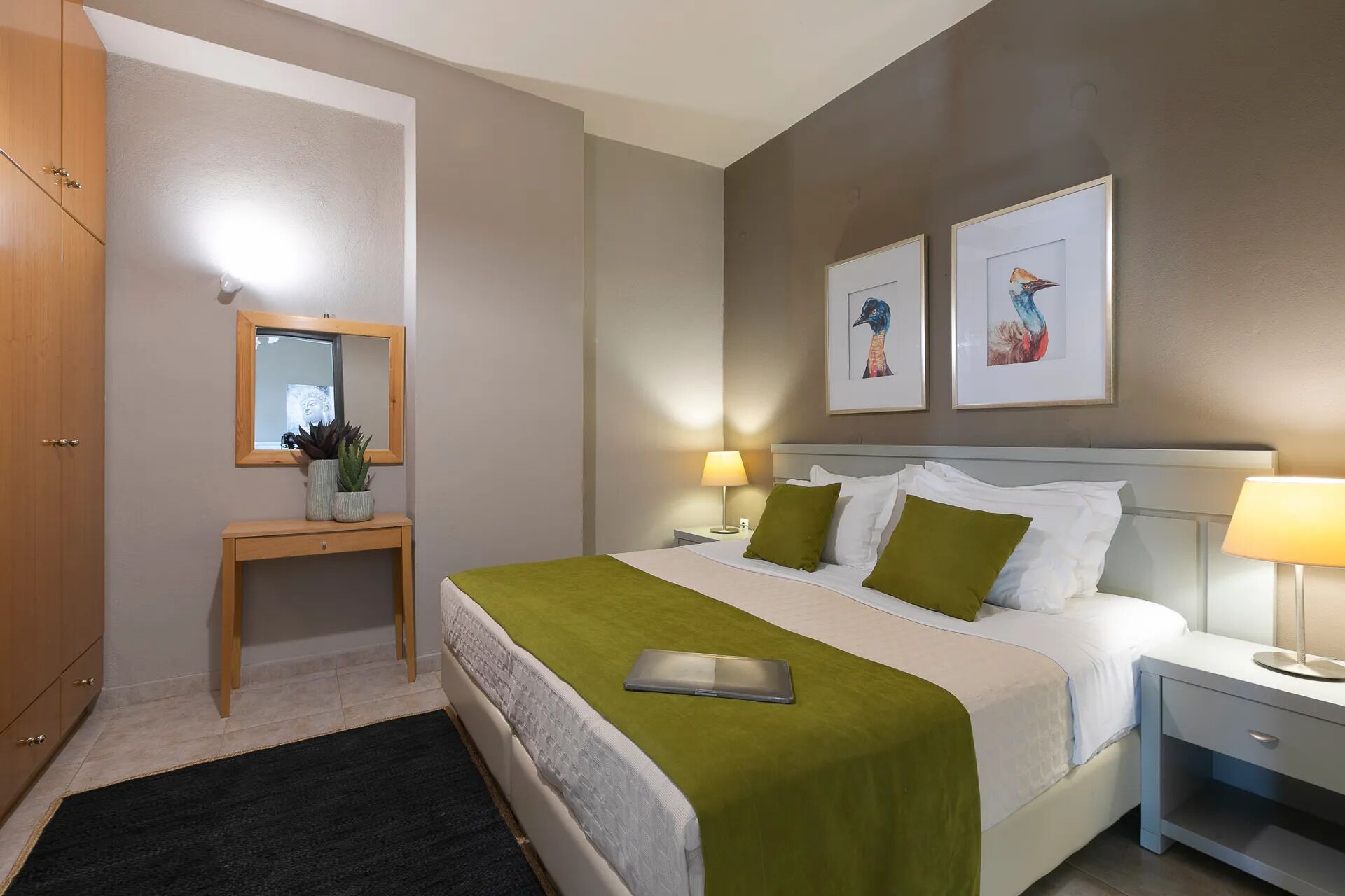 A hotel room with a bed, bedside table, lamp, and artwork on the wall.