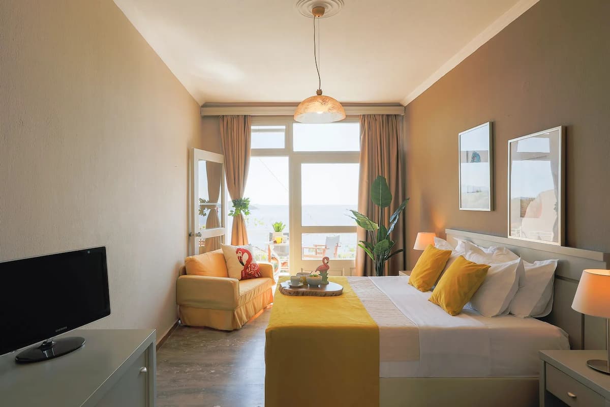 Una habitación de hotel con una cama, un sofá, un televisor y una mesa de comedor.