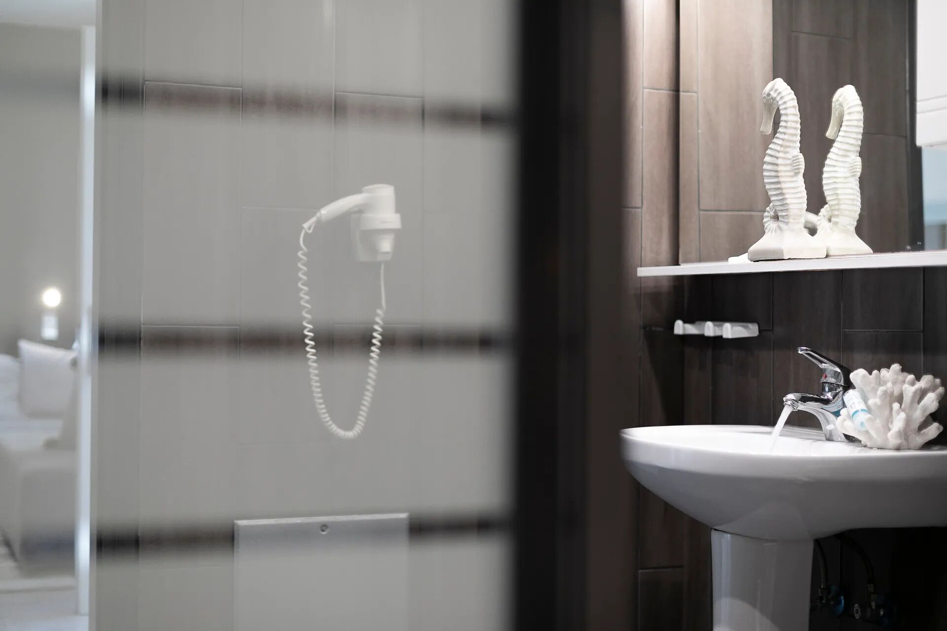 Un bagno dal design moderno, con un lavandino bianco, uno specchio e un soffione.