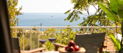 A balcony with a table, chairs, and a bowl of fruit.