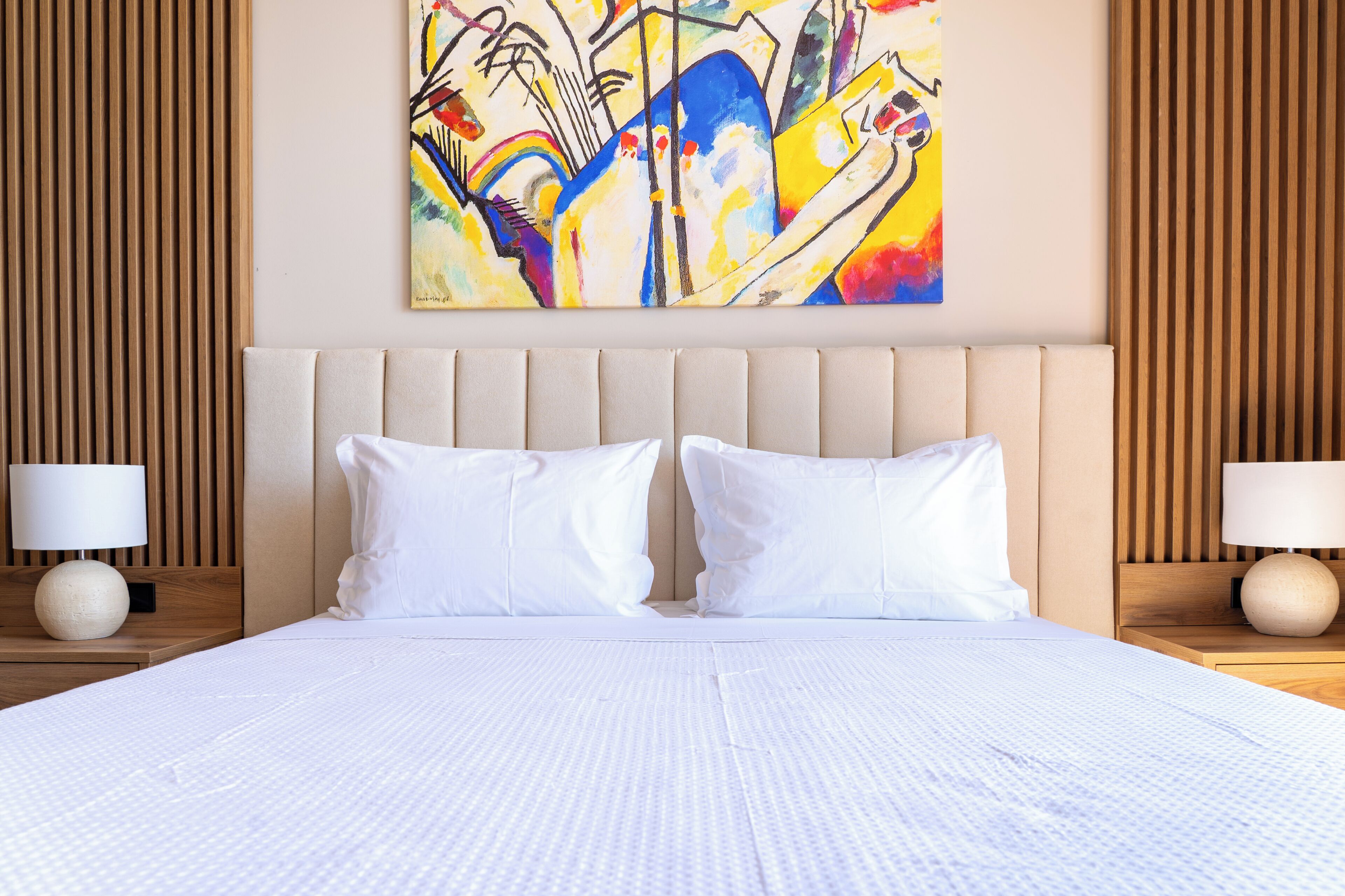 Ein Hotelzimmer mit einem großen Bett, zwei Nachttischen, einem Wandbild und Holzvertäfelung.