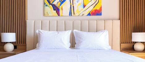 A hotel room with a large bed, two bedside tables, a wall-mounted painting, and wooden paneling.