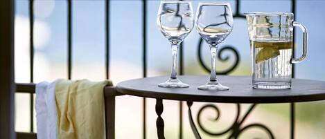 A table with two wine glasses and a pitcher on a balcony.