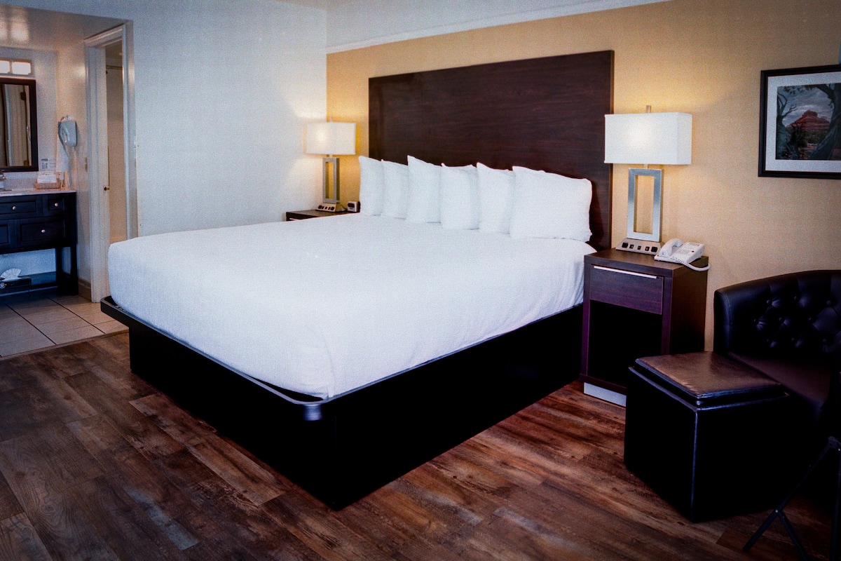 A hotel room with a large bed, bedside lamps, a desk, and a chair.