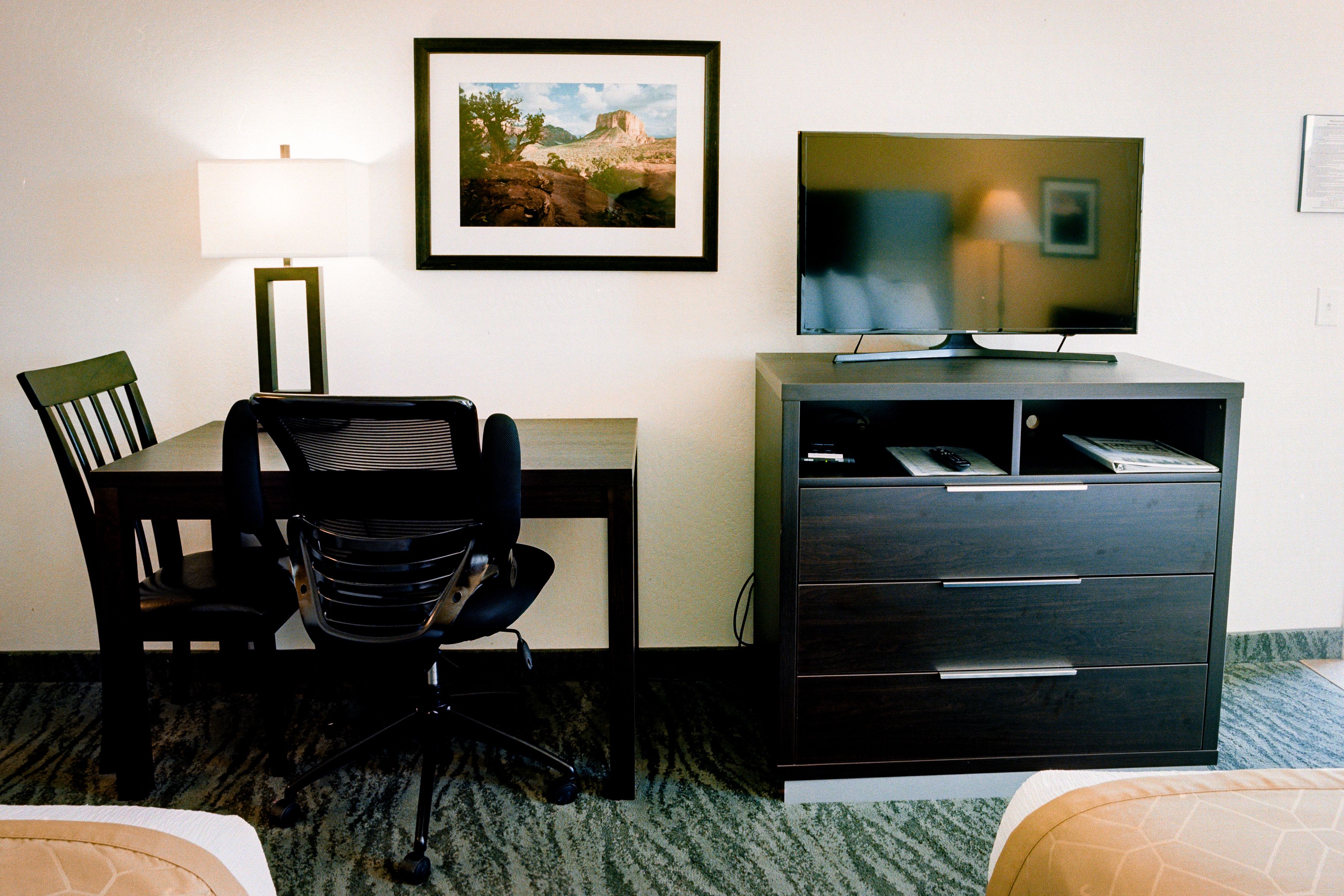 Une chambre d’hôtel équipée d’un bureau, d’une chaise, d’une télévision et d’un placard.