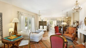 Un amplio salón con una mesa de ajedrez, un sofá y una zona de comedor con sillas.