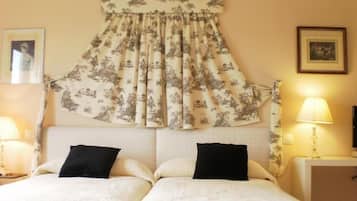 A double bed with two black pillows, a floral curtain, and two bedside lamps.