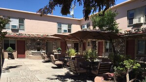 An outdoor patio area with stone flooring, outdoor seating, and a stone wall. - The Iron Horse Inn (Cottonwood)