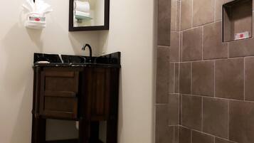 Un baño con tocador, espejo, perchero para toallas y ducha con azulejos perforados.