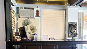 A reception desk with a dark wood finish, a potted plant, and a mounted decorative item on the wall. - The Iron Horse Inn (Cottonwood)