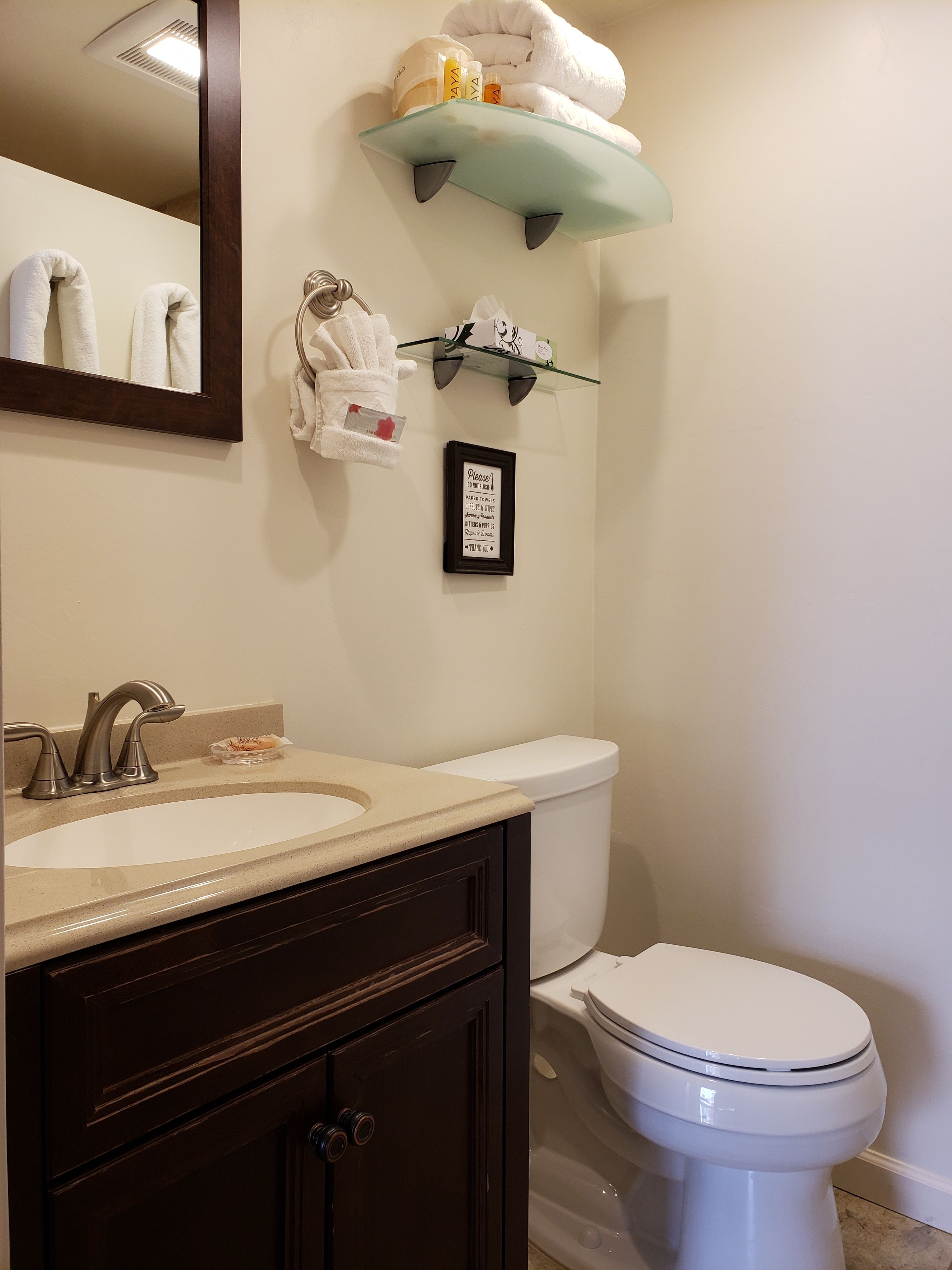 Ein Badezimmer mit Waschbecken, Spiegel, Handtuchhalter und Toilette.