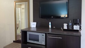 A hotel room with a TV, microwave, and a coffee maker on the counter.