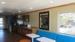 A modern interior with a kitchen area, seating with orange ottomans, and a large window offering a view of the outside.