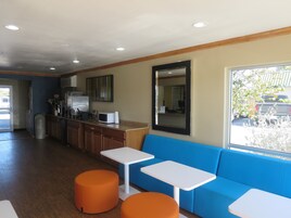 Un interior moderno con una zona de cocina, asientos con otomanas naranjas y un ventanal que ofrece vistas al exterior.