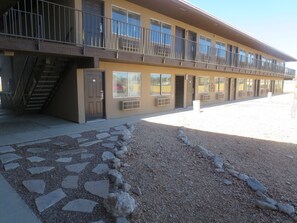 A building with a flat roof, multiple windows, and a staircase leading to an upper level.