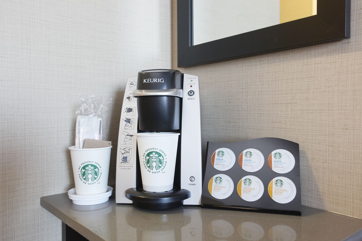 A Keurig coffee machine with a coffee cup and a coffee pod holder on a counter.