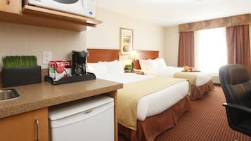 Een hotelkamer met twee bedden, een magnetron, koffiezetapparaat, wastafel en stoel.