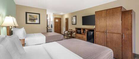 A hotel room with two beds, a desk with a chair, a television, and a wardrobe.