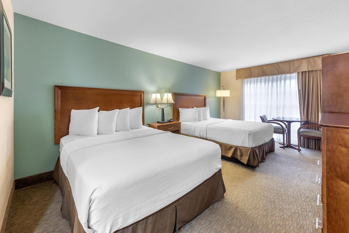 A hotel room with two beds, a desk, and a chair.