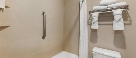 A bathroom with a bathtub, a toilet, a shower curtain, and a towel rack with towels.