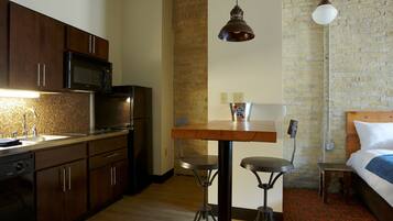 Una cocina compacta equipada con microondas, refrigerador y una mesa de madera con taburetes de bar.